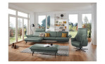Basis-Ecksofa 1928 in der Farbausführung grün mit Dekokissen, einem Hocker und einem Sessel im Raum stehend
