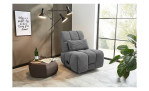 Relax-Sessel in grauem Cordstoff bezogen mit einem Zierkissen im Wohnzimmer.