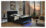 Boxspringbett Jogi in Anthrazit aus einem Stoffbezug mit einer Lichtleiste im Fußteil. Auf einem dekorierten Hintergrund.